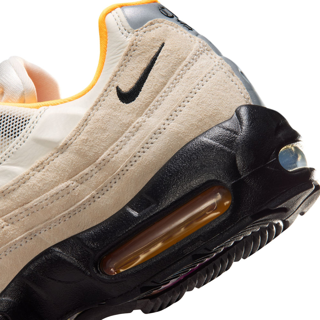 Close-up of a Nike sneaker with beige, black, and orange accents on a white background