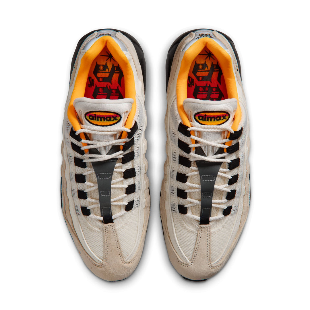 Pair of beige sneakers with black and orange accents on a white background