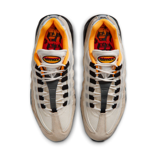 Pair of beige sneakers with black and orange accents on a white background