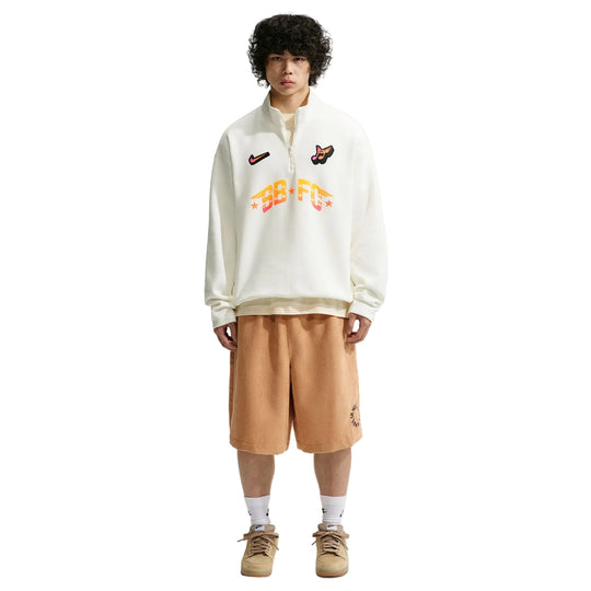 Person wearing a white sweatshirt with colorful text and graphics on a plain background