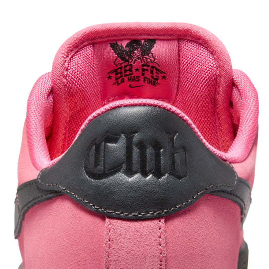 Close-up of a pink sneaker with a black strap and visible brand logo on a white background