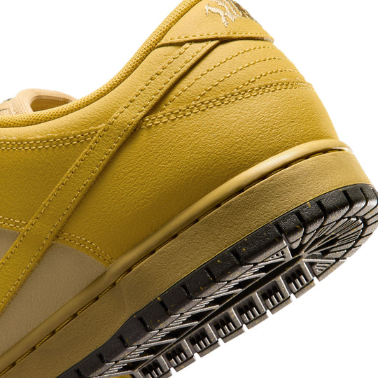 Close-up of a low-top sneaker showing the heel and side panel in a mustard yellow colorway, with a black treaded outsole and a small tonal logo near the collar.