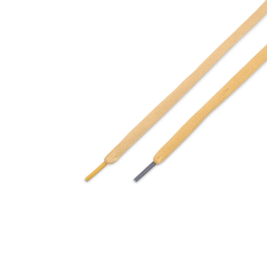 Two flat shoelaces in a light tan color, shown diagonally on a plain white background. One lace tip is yellow, and the other has a dark metal eyelet.