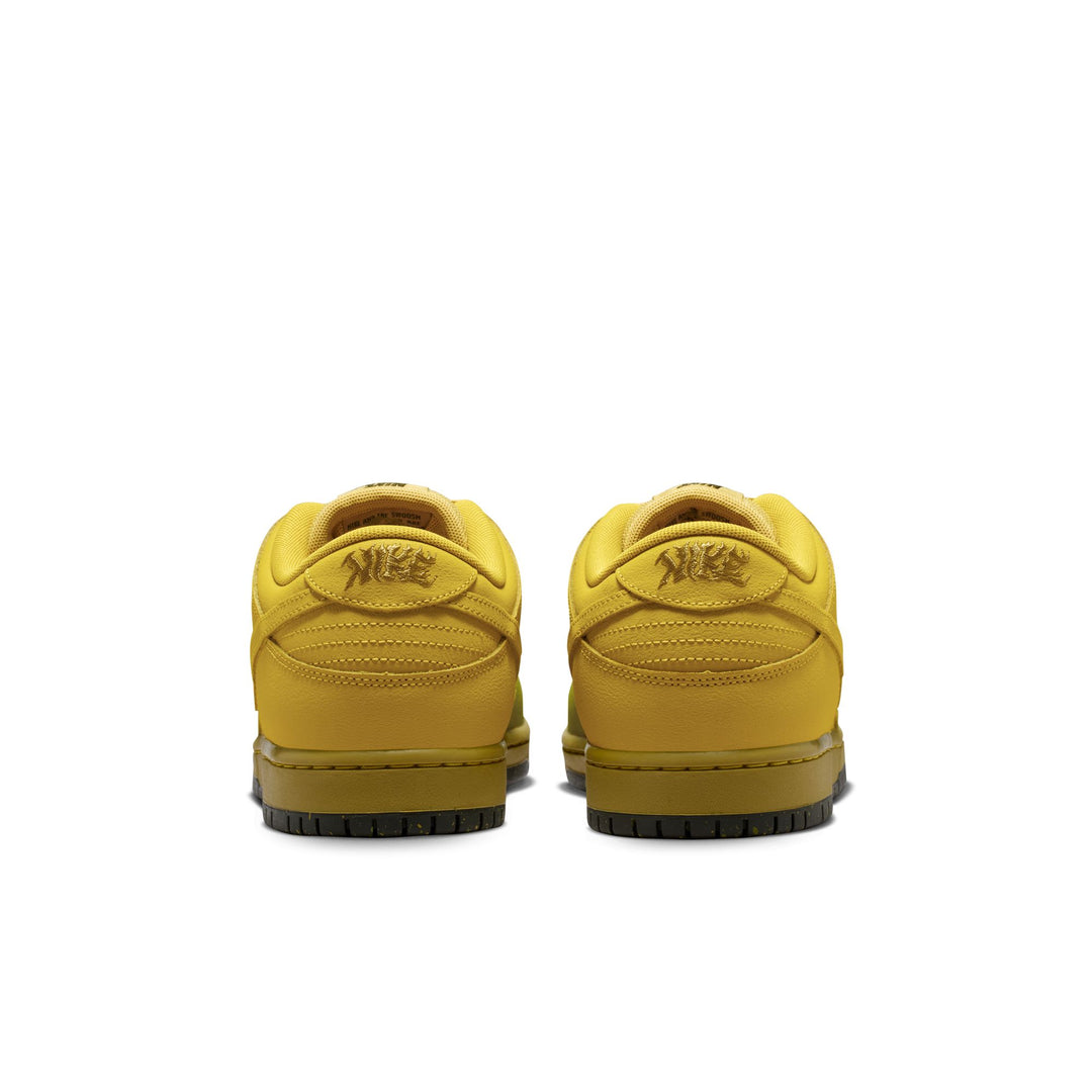 A pair of Nike low-top sneakers shown from the back, featuring a mustard yellow leather upper with a tonal yellow Nike logo on the heel and a dark olive-yellow sole.