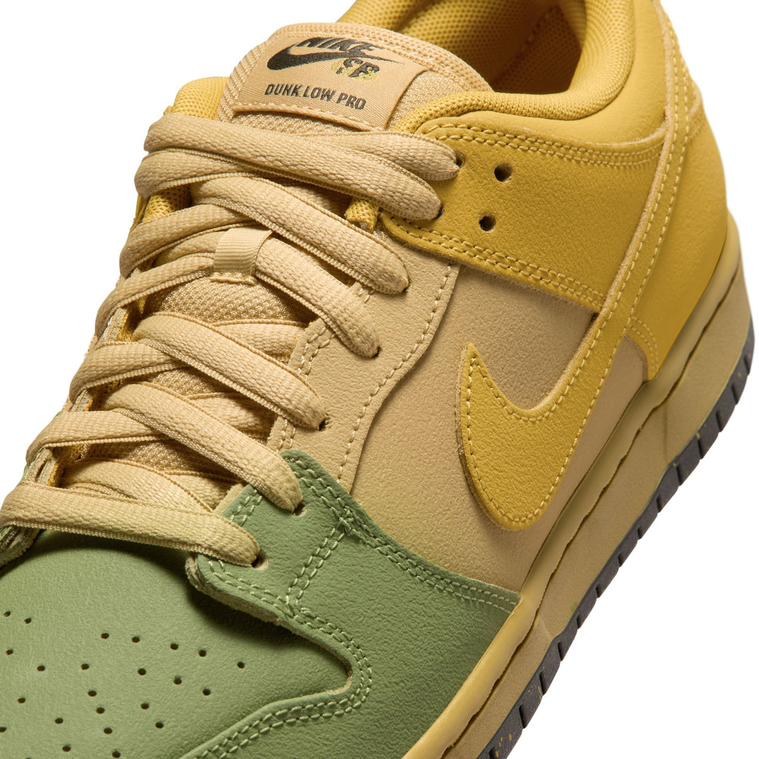 A close-up of a Nike Dunk Low Pro sneaker in a yellow, beige, and sage green colorway, showing the side profile with the Swoosh on a white background.