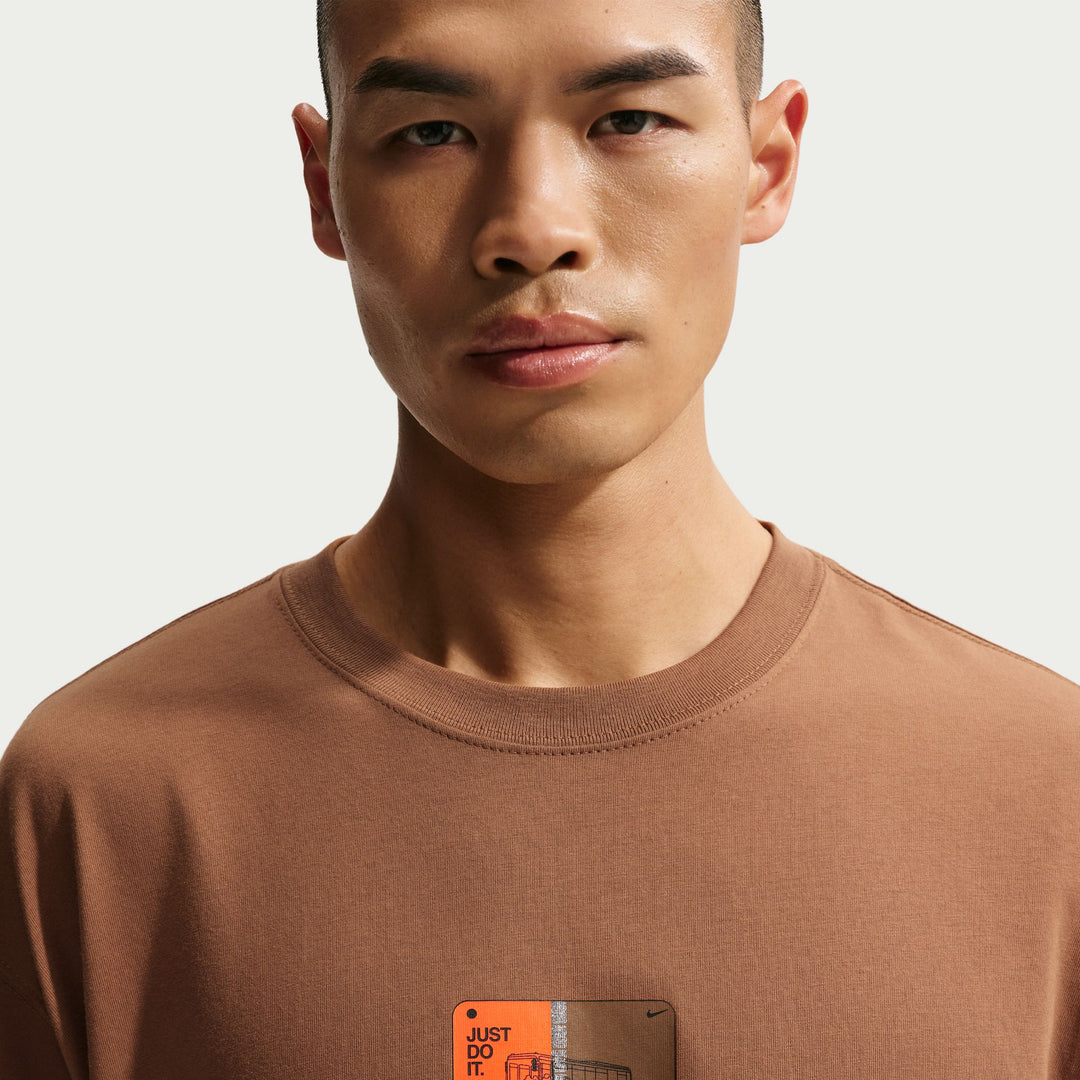 Man wearing a brown t-shirt with a visible brand logo 