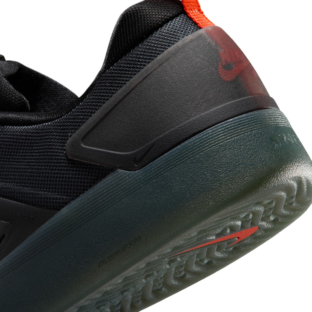 Close-up of a black and gray sneaker with red accents on a white background