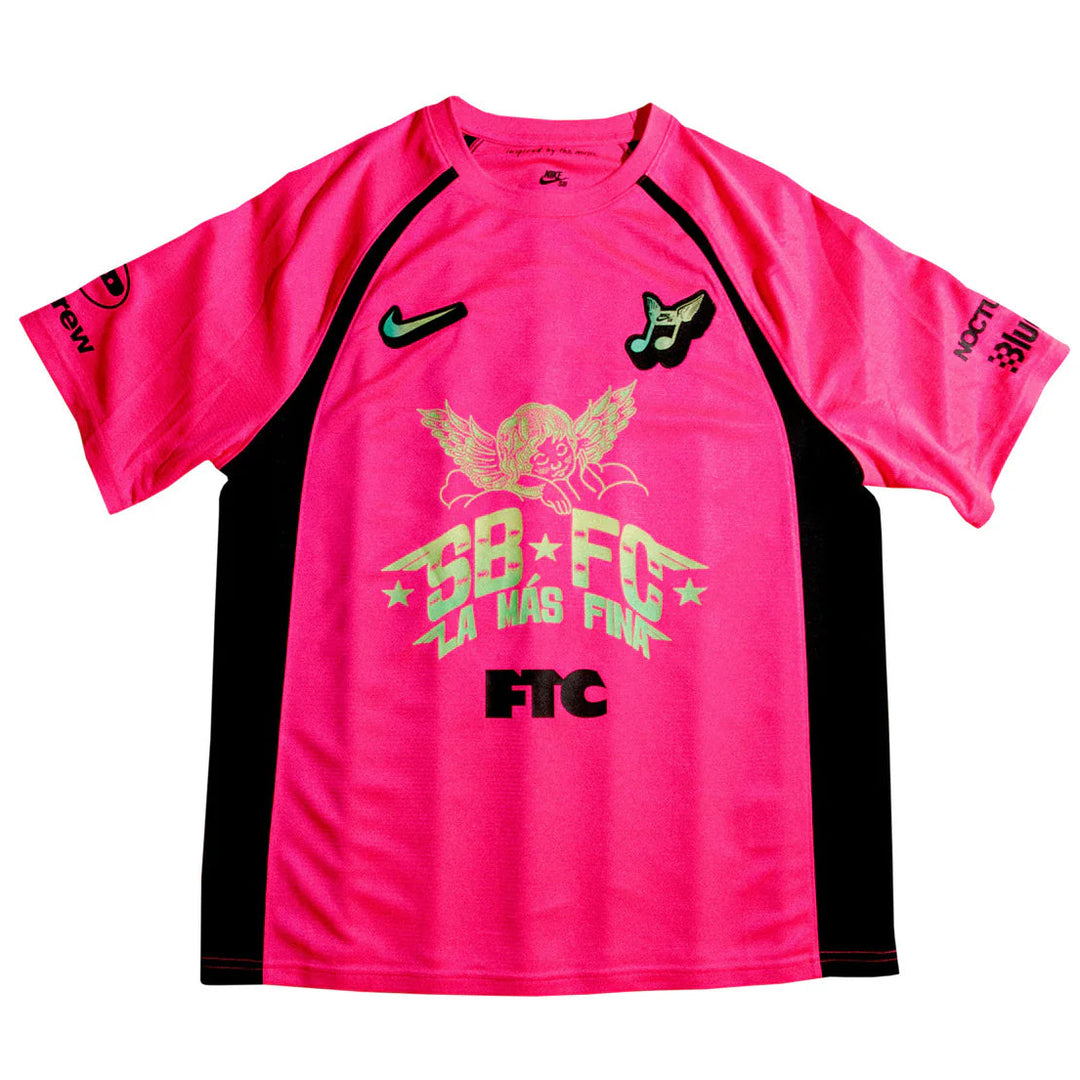 A bright pink Nike soccer jersey with black side panels and a large gold and black graphic on the front reading 'SB FC LA WAS FAN'.