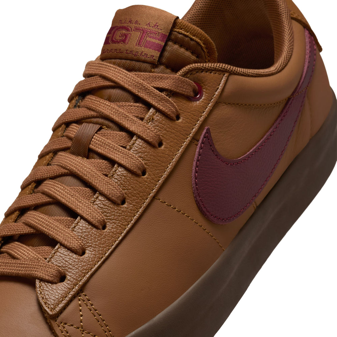 Brown sneaker with maroon swoosh logo on a white background