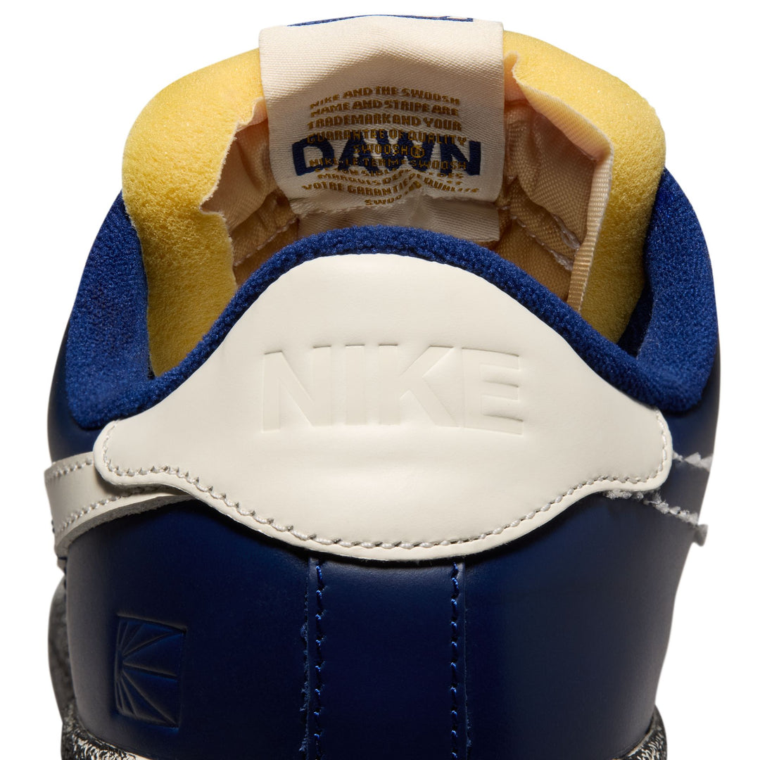 Close-up of a blue and yellow shoe with a visible brand label on a white background