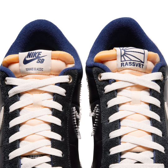Pair of navy and peach sneakers with white laces on a white background