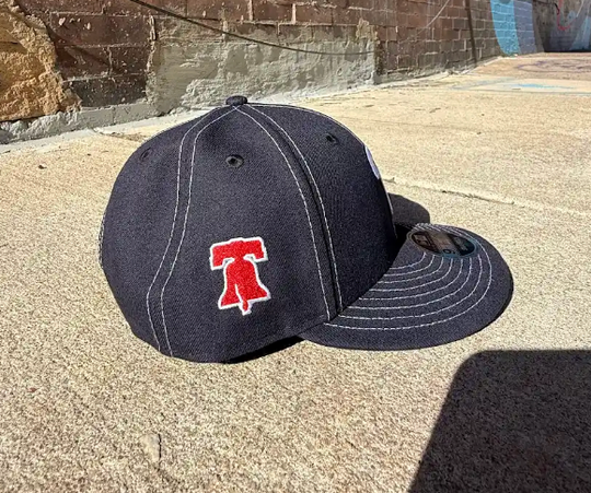 Black baseball cap with a red logo on a concrete surface