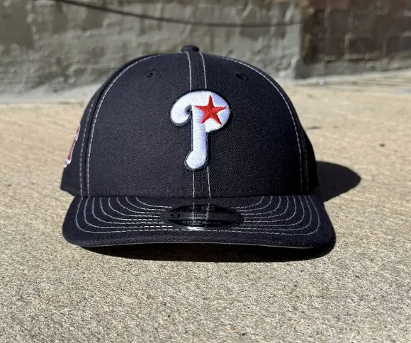 navy baseball cap with a red star logo on a concrete surface