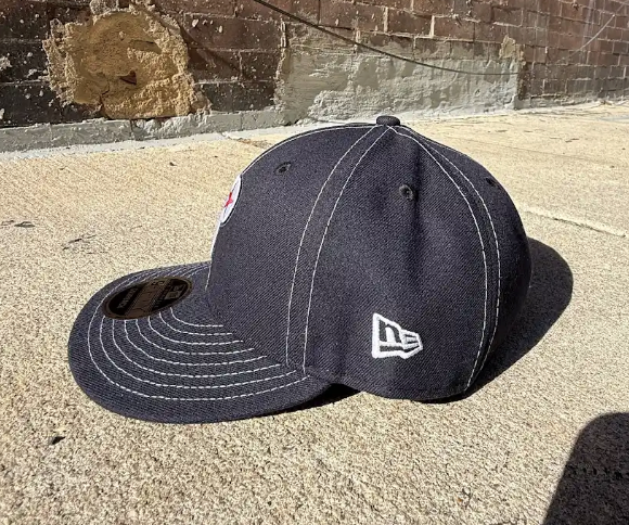 Black baseball cap with New Era logo on a concrete surface
