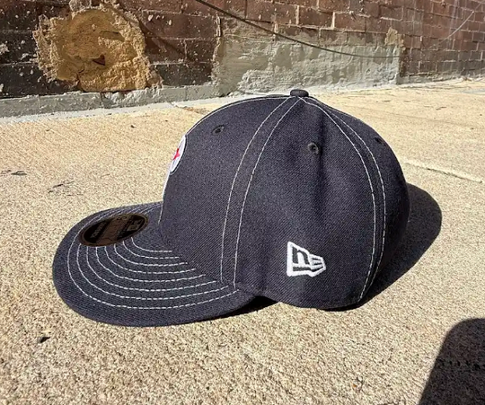 Black baseball cap with New Era logo on a concrete surface