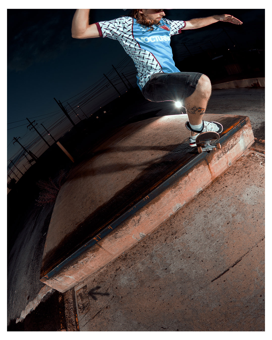 Skateboarder performing a trick on a ledge at night.