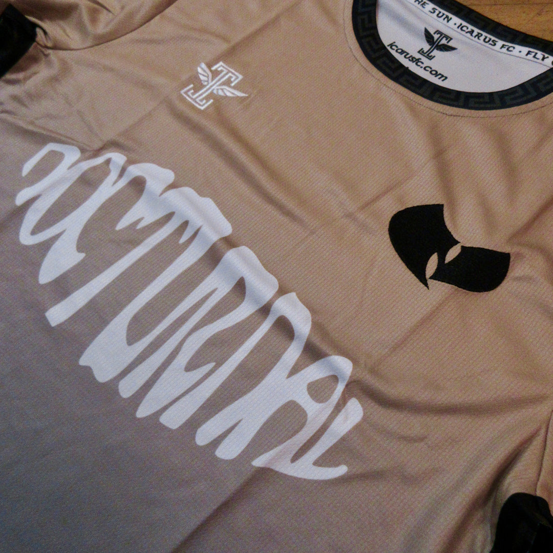 Beige sports jersey with white text and black logo on a wooden surface