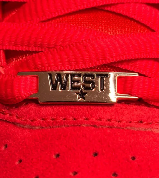 Close-up of red shoelaces with a metallic 'WEST' logo 