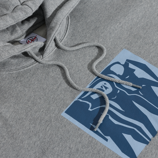 Gray hoodie with a brand label on a gray surface next to a blue and white polar graphic print.