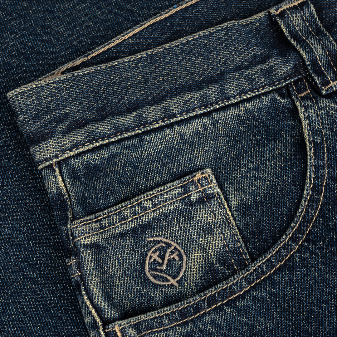 Close-up of blue denim jeans with a brand logo on the pocket.