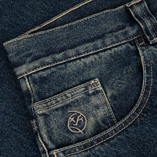 Close-up of blue denim jeans with a brand logo on the pocket.