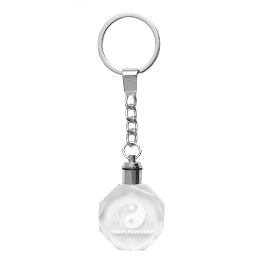 Keychain with a clear glass ball and yin yang symbol on a white background
