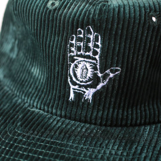 Dark green corduroy bucket hat with a white embroidered design on a light gray background
