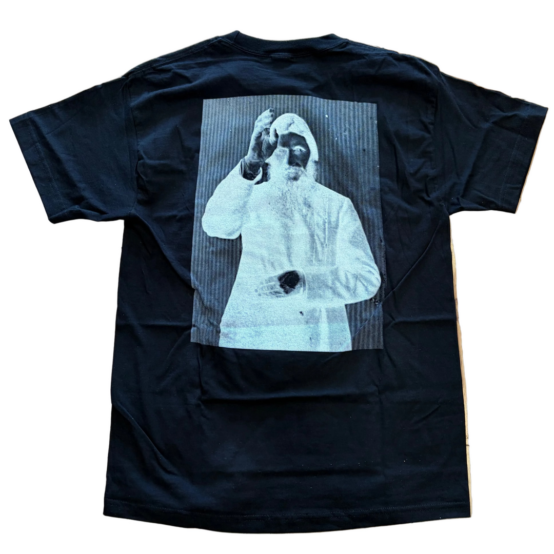 Black t-shirt with a graphic design on the back, placed on a wooden floor.