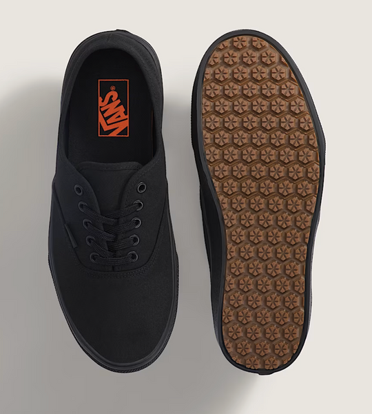 Black sneaker with brown sole on a light gray background