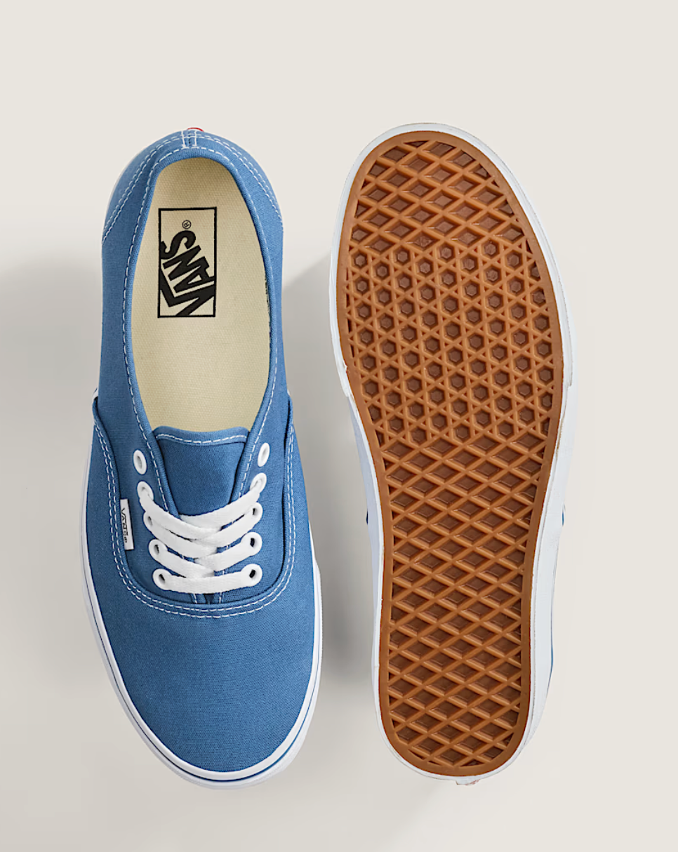 A pair of Vans platform sneakers in blue canvas, shown from a top-down view. One shoe is oriented to show the blue suede upper, white laces, and the black Vans logo printed on the beige insole.