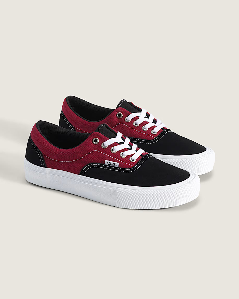 Black and red sneakers with white laces on a light gray background