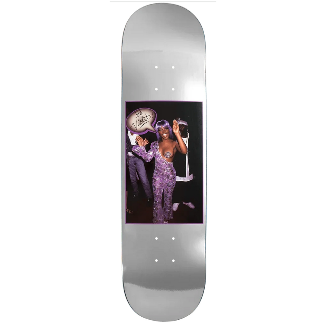 A silver skateboard deck featuring a rectangular graphic print in the center with a photo of a person in a purple outfit and a sign that reads 'it's violet'.