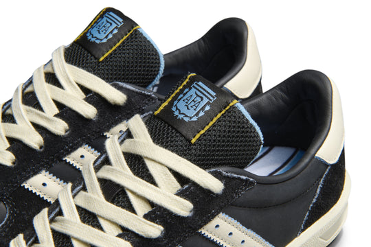 Black sneakers with white laces and blue accents on a white background