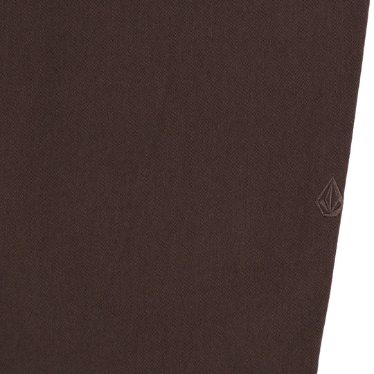 Close-up of brown pants with a brand logo on a white background