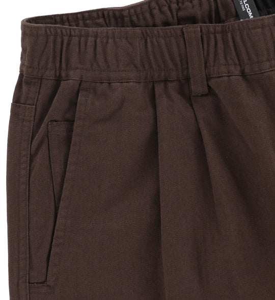 Close-up of brown pants with a brand label on a white background